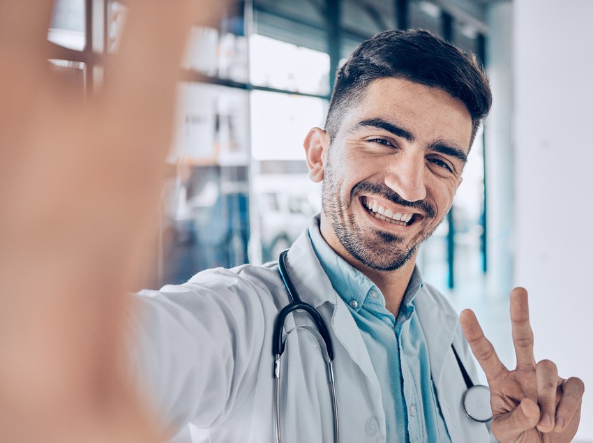 A male doctor confidently making a peace sign while studying for the MCCQE1 exam using Ace QBank.