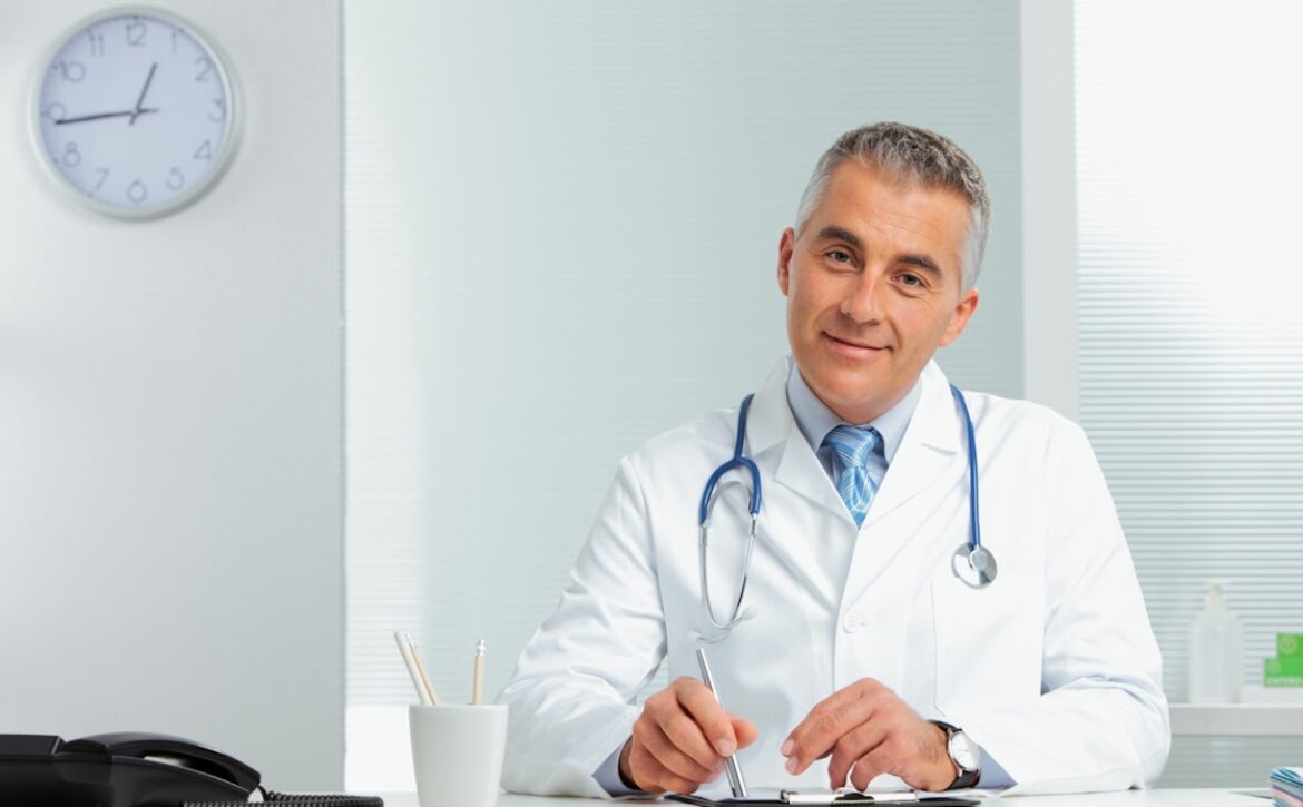 A male doctor is sitting at his desk, wearing a white coat, discussing using Ace QBank to prepare for the MCCQE1 exam.