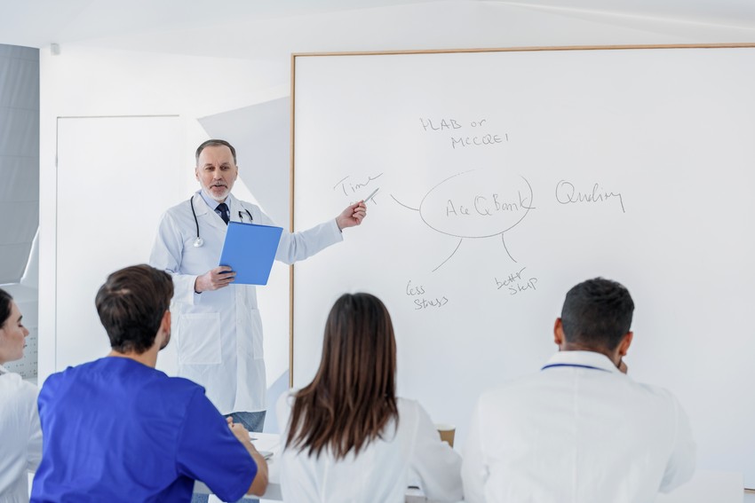 A medical instructor teaching a class on PLAB with attentive students.