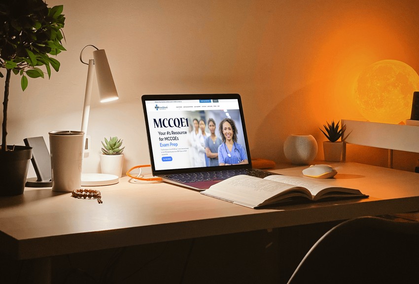 A well-organized desk with a laptop showing an MCCQE1 question bank in Ace Qbank a healthcare website, a lamp, decorative plants, and an open question bank book.