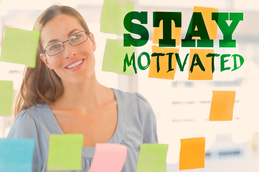 Smiling medical student wearing glasses, standing in an office with colorful sticky notes, with the phrase "stay motivated" in bold letters above her.