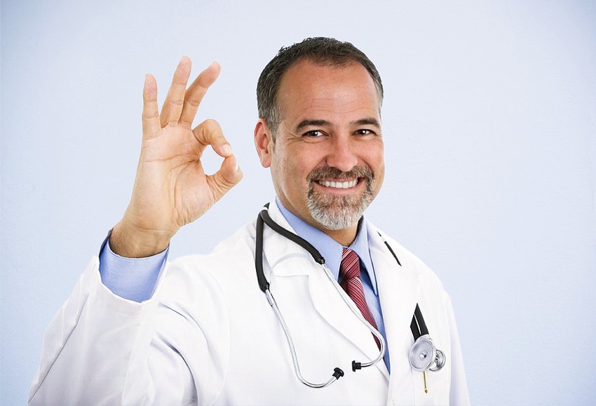 A smiling male doctor in a white coat is making an "ok" sign with his hand against a light blue background saying MCCQE part 1 is great.