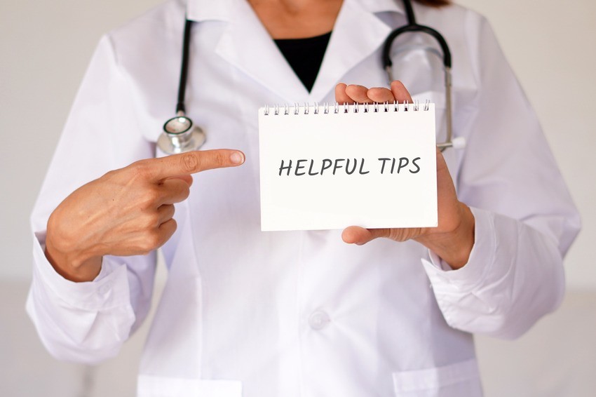 A doctor in a white coat points to a notepad with "Helpful Tips" written on it, offering insights for MCCQE1 exam preparation.