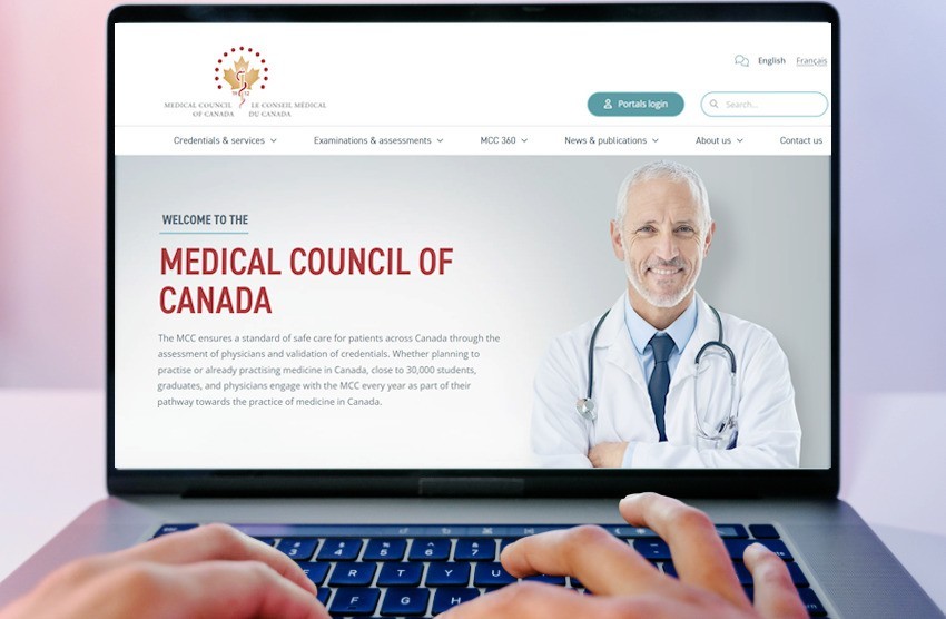 A person types on a laptop displaying the Medical Council of Canada's website, with a doctor and navigation menu under the "Welcome to the Medical Council of Canada" heading, focusing on MCCQE1 exam preparation and MCCQE Part 1 scheduling for 2025.