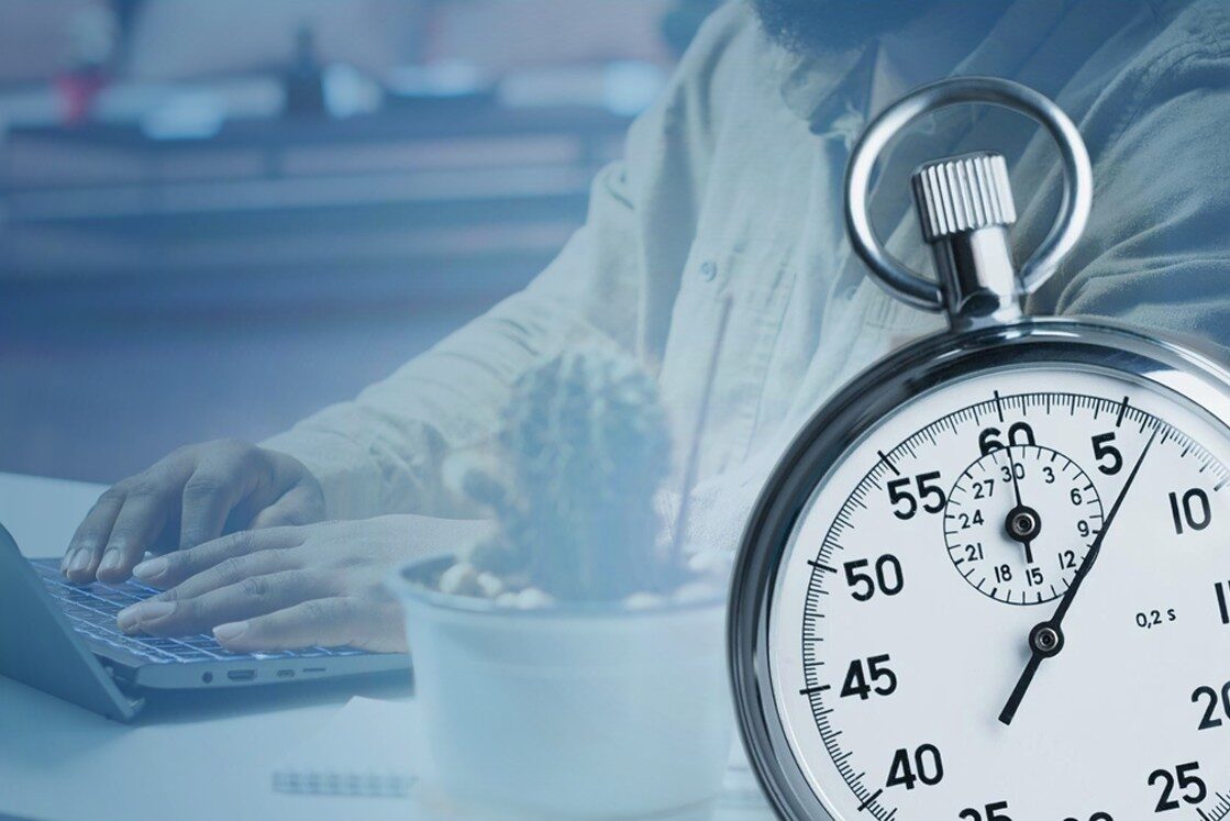 A person types on a laptop at a desk with a small potted plant, while a large stopwatch shows roughly 22 seconds. capturing the focus and efficiency needed for MCCQE1 exam preparation with Ace QBank.