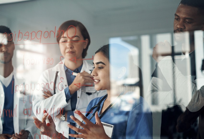 Medical professionals discuss notes on a transparent board in a clinical setting, sharing 3 essential tips for studying MCCQE1 to enhance effective MCCQE1 exam preparation.