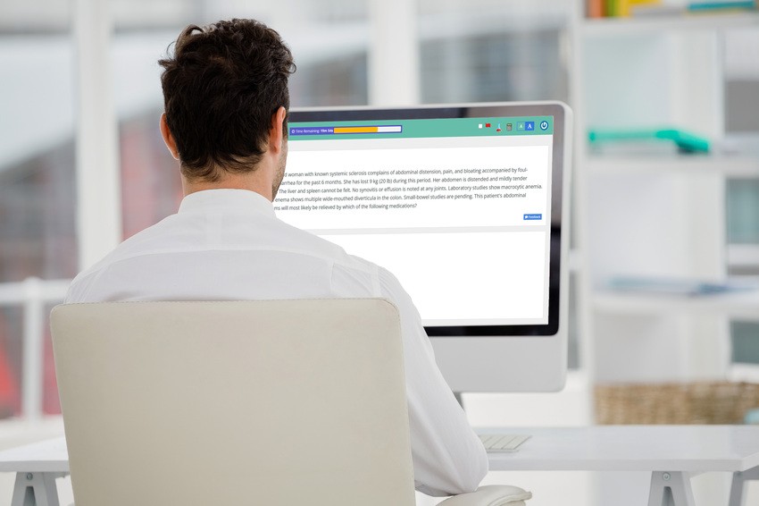 A man with dark hair sits at a desk and looks at a computer monitor. Using Ace QBank to prepare for the MCCQE1 exam in the hope of the best MCCQE1 result.