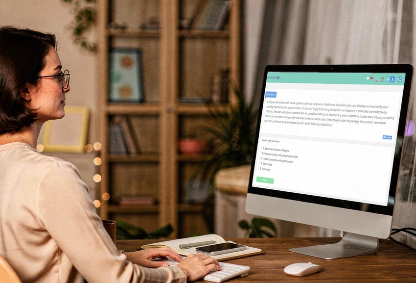 A woman sits at a desk using a desktop computer, reading a multiple-choice question from Ace QBank. The best Qbank for MCCQE1 exam preparation.